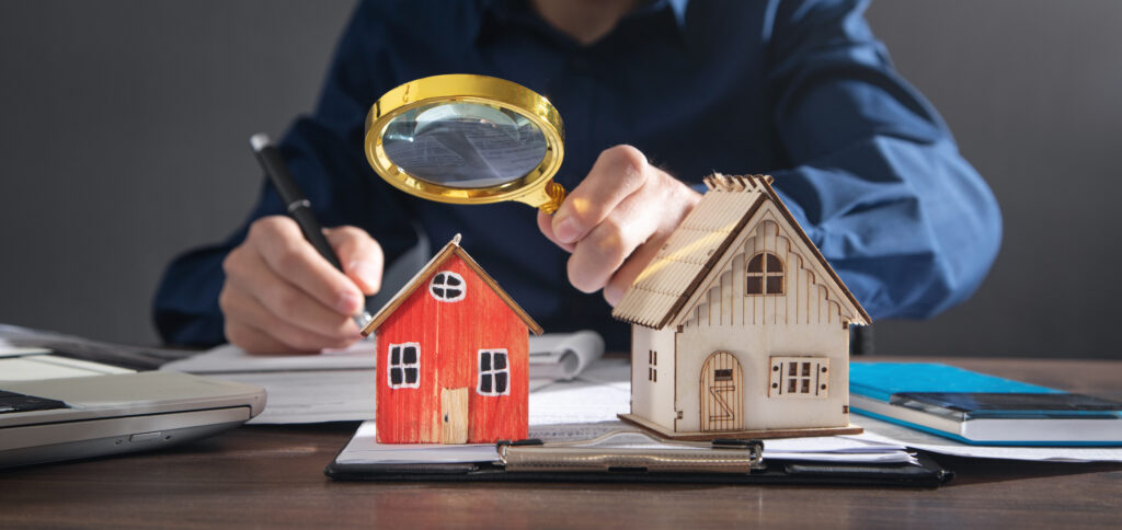 House model on the desk. Real estate agent holding magnifying glass